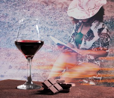 Red wine glass with chocolate and woman portrait reading book with sunset cloudscape clipart