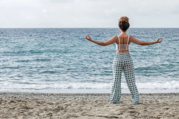 Retrato de mulher praticando ioga na praia enquanto olha para o mar — Fotografia de Stock