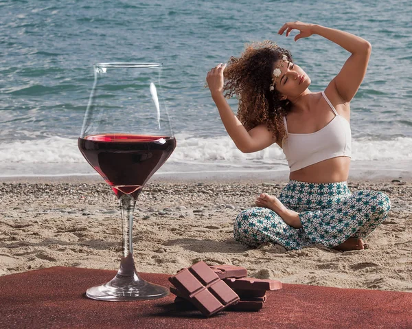 Copa de vino tinto con chocolate y hermoso retrato de mujer sentado en la playa — Foto de Stock