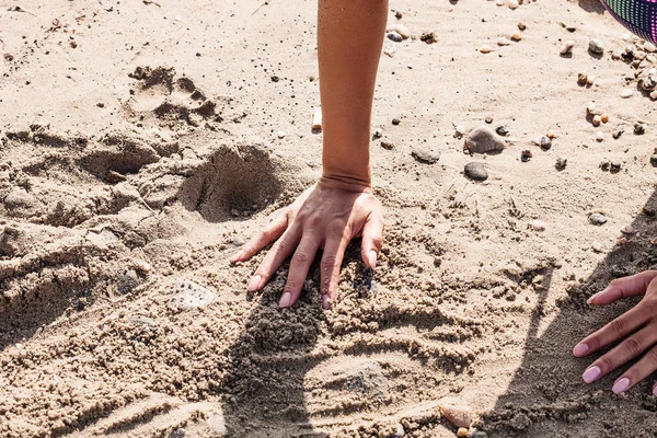 Female hands playing with the sand on the beach — Stock Photo, Image