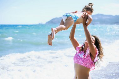 Holding ve küçük kızıyla birlikte sahilde oynarken mutlu anne