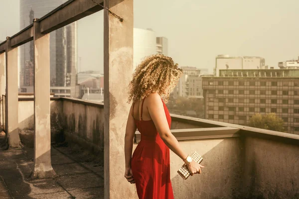 Retrato de mulher bonita e elegante andando no telhado da construção sob a luz solar — Fotografia de Stock