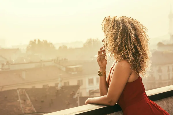 Retrato de mulher bonita e pensativa com cabelo encaracolado lindo olhando para paisagem urbana — Fotografia de Stock