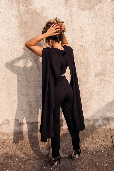 Elegante Frau zurück Porträt trägt schwarzes Kleid und Einstellung ihrer Haare — Stockfoto