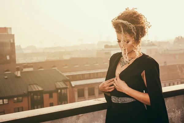 Элегантный женский портрет в черном платье и стоя на крыше — стоковое фото