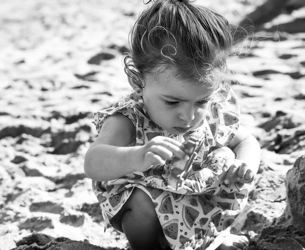 Menina bonito brincando com brinquedos de areia enquanto vestindo vestido de melancia, monocromático — Fotografia de Stock