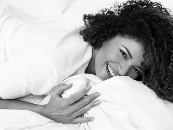 Happy woman laughing while lying on bed in the morning, monochrome — Stock Photo, Image
