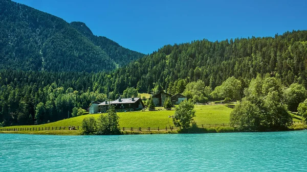 Pine woods, cottages and beautiful blue lake in North Italy mountains — Stock Photo, Image