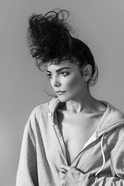 Sensual woman with messy bun wearing hoodie and looking aside, monochrome