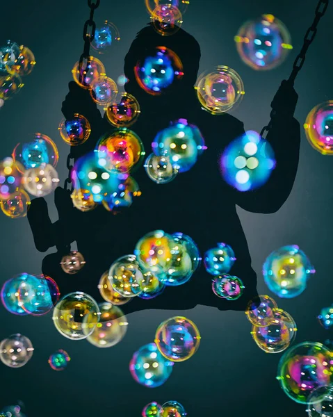 Dubbel exponering av kid på swing och färgglada såpbubblor — Stockfoto