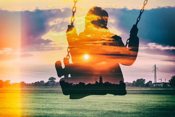 Double exposure of kid on swing and gorgeous sunset in the countryside — Stock Photo, Image