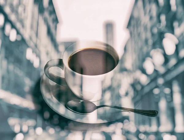 Double exposure of cup of coffee and blurred cityscape