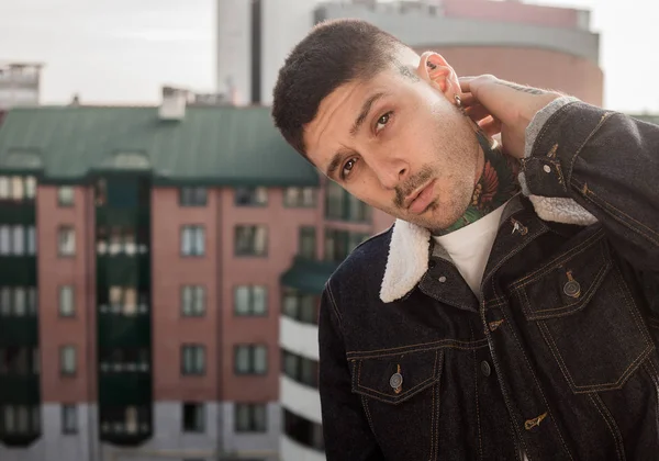 Handsome man portrait wearing jeans jacket with tattoos on neck and hand — Stock Photo, Image