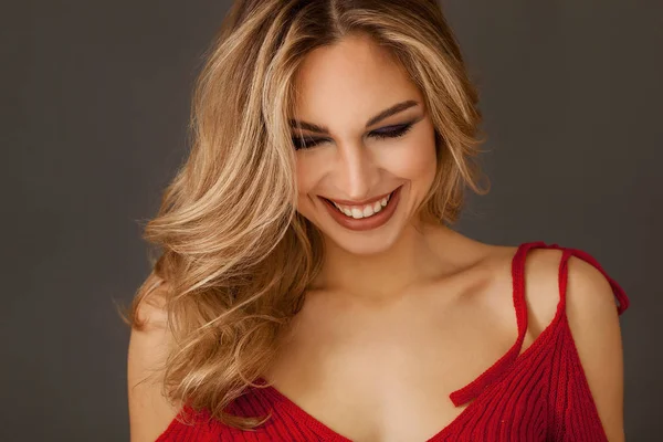 Gorgeous blonde woman portrait wearing red dress and smiling widely