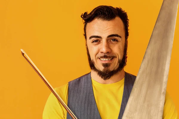 Hombre primer plano retrato sosteniendo sierra musical y sonriente, horizontal — Foto de Stock