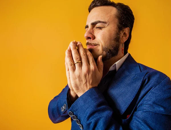 Man portrait going to sneeze, wearing blue jacket on yellow background