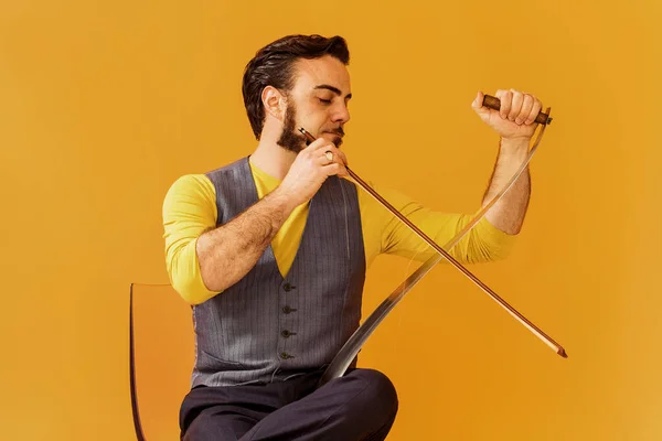 Portrait d'homme assis sur une chaise et jouant de la scie musicale — Photo