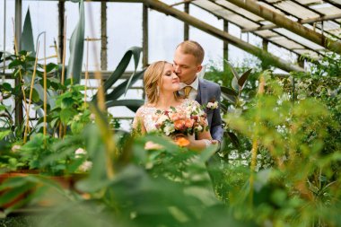bride and groom in a greenhouse