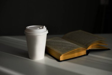 beyaz karton bardak ve kitap. Düşük tuşlu fotoğraf