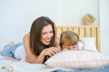 mom and daughter are lying in bed and laughing