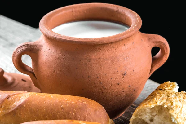 Глиняный горшок с молоком и багетом — стоковое фото