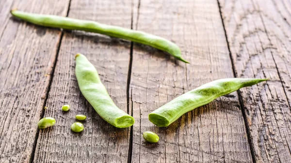 Groene bonen peulen op een houten tafel — Stockfoto