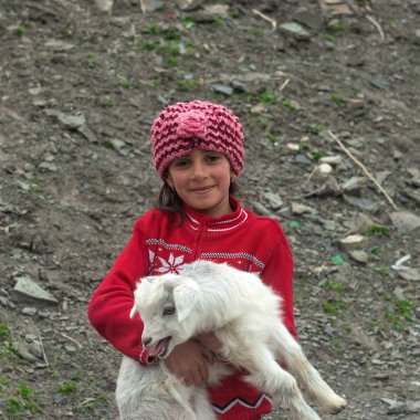 Küçük kız beyaz bir goatling onun elinde tutuyor
