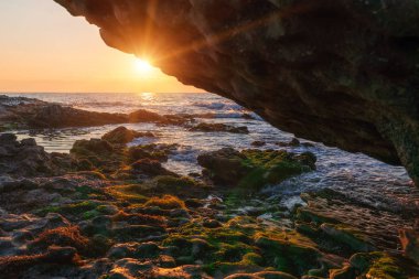 Kayalık bir sahilde renkli bir gün doğumu