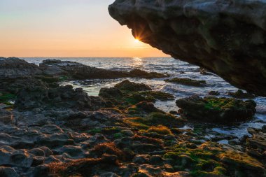Kayalık bir sahilde renkli bir gün doğumu