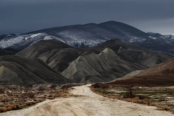 Dirt road to the mountains at stormy weather — Stock Photo, Image