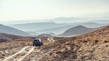 Hyundai Tucson dağlık arazide toprak yolda.