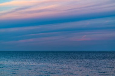 Alacakaranlıkta ufuk çizgisi olan mavi deniz
