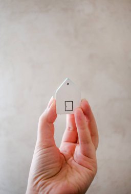 Küçük beyaz bir evi tutan el.