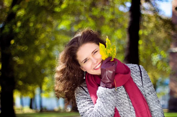 Glücklich lächelnde junge Frau mit einem Bund gelb gefärbter Ahornblätter — Stockfoto