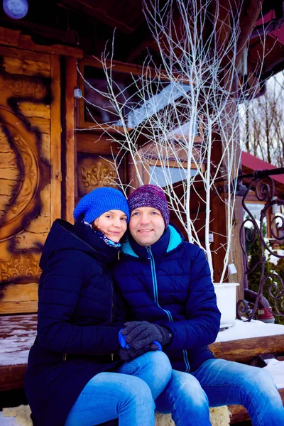 Фото молодой красивой пары в зимней одежде, сидящей снаружи — стоковое фото