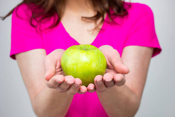 Подходящая женщина в розовой рубашке, молодая женщина с яблоком. не изолированы
