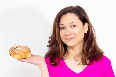 Pembe gömlekli uygun kadın kruvasan yemek istiyor, kruvasan kız genç kadınla kruvasan yemek için tereddüt. izole değil