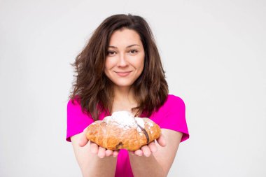 Pembe gömlekli uygun kadın kruvasan yemek istiyor, kruvasan kız genç kadınla kruvasan yemek için tereddüt. izole değil