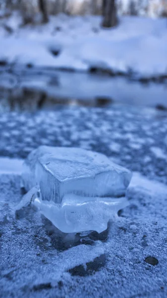 Donmuş bir nehrin arka planında, buz gibi bir yüzey üzerinde bir buz parçası.