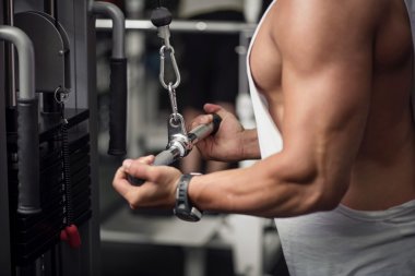 Spor salonu aparatının yanında duran iyi inşa edilmiş atletik adam