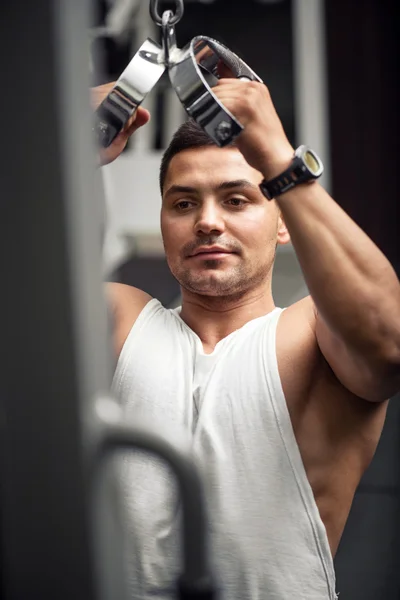 Boa aparência atlético homem formação em um aparelho de ginásio — Fotografia de Stock