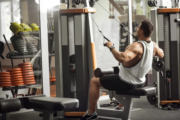 Fuerte entrenamiento de deportista profesional en un aparato de gimnasio — Foto de Stock