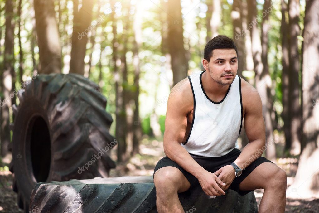 Handsome thoughtful man sitting on the tire