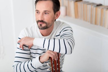 Esmer yakışıklı bir müzik aleti yaslanmış