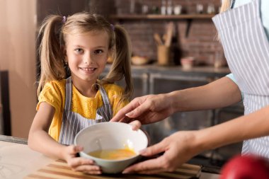 Çok mutlu kızı annesi bir kase tutarak