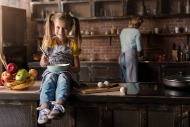 Mutlu kız mutfakta masada yumurta karıştırma