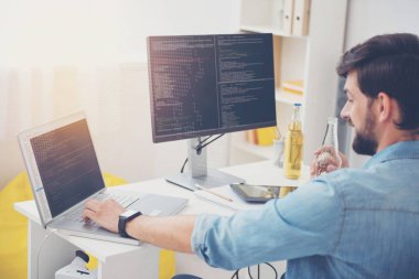 Yakışıklı programcı rahat bir ofiste dizüstü bilgisayar kullanarak