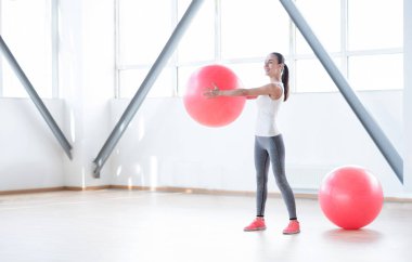 Bir fitness topu tutan neşeli kendine güvenen kadın