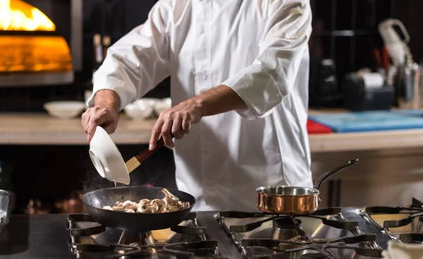 Hårt arbetande kock steka svamp i köket i restaurangen — Stockfoto