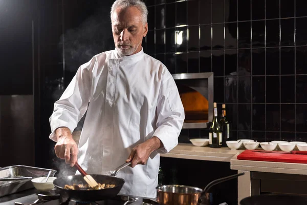 Chef involucrado mezclando setas en la sartén — Foto de Stock